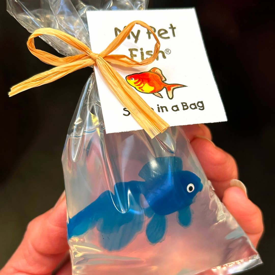 Lifestyle Blue fish in a bag soap with a 'My Pet Fish' label, held by a hand against a dark background.